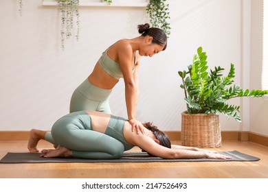 Yoga instructor training child pose with Asian women wearing green sportswear.Healthy Female doing yoga workout exercise.Yoga Teacher teaching Private yoga training at home.Stretching back muscle - Powered by Shutterstock