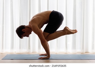 Yoga man performing lolasana or pendant pose on his morning routine. Core training exercise in hand standing