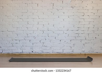 Yoga Mat On The Background Of A White Brick Wall In A Room Without People.