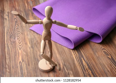 Yoga mat and small mannequin on wooden background - Powered by Shutterstock