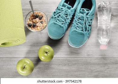 yoga mat with sport shoes and healthy food on a wooden background