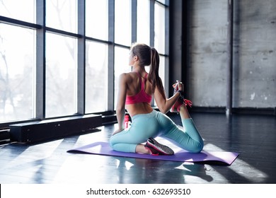 Yoga Mat Woman Stretching Hip, Hamstring Muscles And Groin Area, Leg Muscles With Pigeon Pose Stretch. Fit Asian Fitness Athlete Girl Exercising Sports Stretches In Activewear On Beach At Sunset.