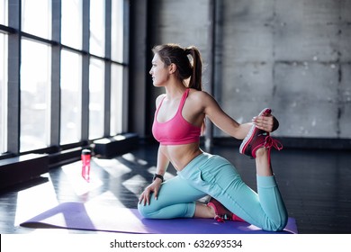 Yoga Mat Woman Stretching Hip, Hamstring Muscles And Groin Area, Leg Muscles With Pigeon Pose Stretch. Fit Asian Fitness Athlete Girl Exercising Sports Stretches In Activewear On Beach At Sunset.