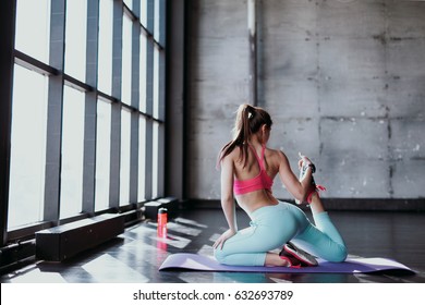 Yoga Mat Woman Stretching Hip, Hamstring Muscles And Groin Area, Leg Muscles With Pigeon Pose Stretch. Fit Asian Fitness Athlete Girl Exercising Sports Stretches In Activewear On Beach At Sunset.