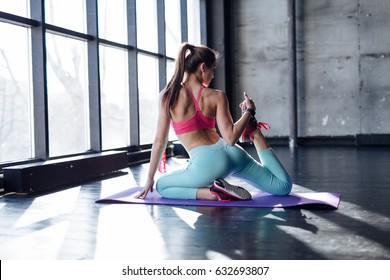 Yoga Mat Woman Stretching Hip, Hamstring Muscles And Groin Area, Leg Muscles With Pigeon Pose Stretch. Fit Asian Fitness Athlete Girl Exercising Sports Stretches In Activewear On Beach At Sunset.