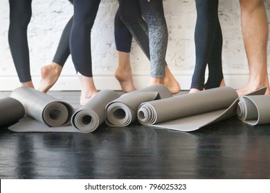 Yoga mats in a roll. Rubber carpets for individual hygiene, soft surface to perform fitness exercises, essential piece of sport gear from nonslip material. Club floor and legs at background. Close up - Powered by Shutterstock