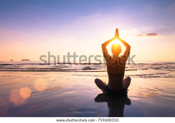 Yoga and meditation on the calm peaceful beach at\
sunset, fit young woman