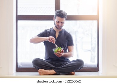 Yoga men with a bowl of vegetable salad, a bottle of water wearing a sportive outfit. Healthy lifestyle concept