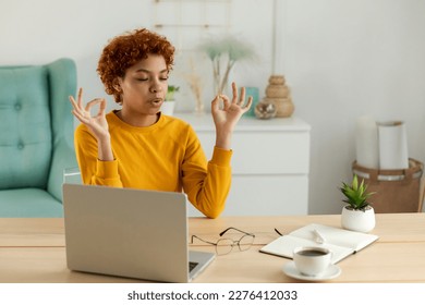 Yoga mindfulness meditation. No stress keep calm. African girl practicing yoga at home office. Woman in lotus pose at office table meditating relaxing indoor. Girl doing breathing practice at work - Powered by Shutterstock