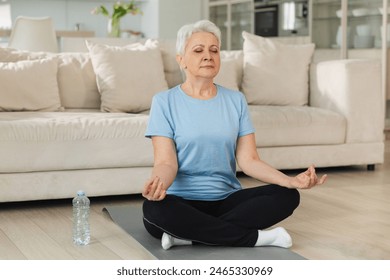 Yoga mindfulness meditation. Senior adult mature woman practicing yoga at home. Mid age old lady sitting in lotus pose on yoga mat meditating relaxing. Older middle aged woman doing breathing practice - Powered by Shutterstock