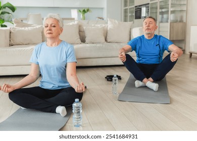 Yoga mindfulness meditation. Senior adult mature couple practicing yoga at home. Mid age old husband wife sitting in lotus pose on yoga mat meditating relaxing. Family doing breathing practice - Powered by Shutterstock