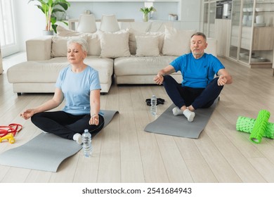 Yoga mindfulness meditation. Senior adult mature couple practicing yoga at home. Mid age old husband wife sitting in lotus pose on yoga mat meditating relaxing. Family doing breathing practice - Powered by Shutterstock