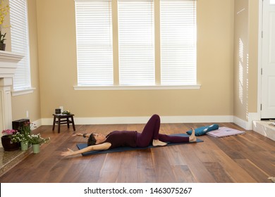 Yoga on back arms overhead one knee bent