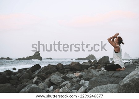 Yoga on the beautiful wild beach. Woman practicing yoga on coastline of the ocean. Active Travel Healthy Yoga Lifestyle. Female health for body and mind. Image of Fitness, Conscious Living, Meditation
