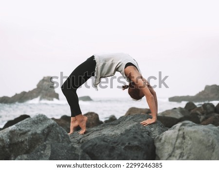 Yoga on the beautiful wild beach. Woman practicing yoga on coastline of the ocean. Active Travel Healthy Yoga Lifestyle. Female health for body and mind. Image of Fitness, Conscious Living, Meditation