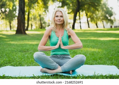 Yoga on fitness mat in green public park forest. Mature beautiful woman practicing meditation relaxing feeling zen-like - Powered by Shutterstock