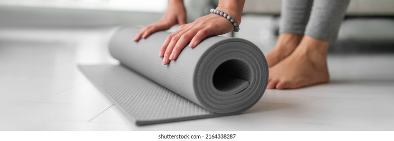 Yoga online class at home woman rolling mat on apartment floor for gym training or meditation banner panoramic. Feet and hands closeup - Powered by Shutterstock