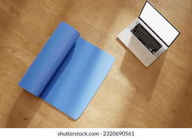 yoga online with mockup latop. Yoga practice, meditation, learning and edication. Blue mat and laptop with blank white screen. View from above. Blue yoga mat on floor with laptop with copy space