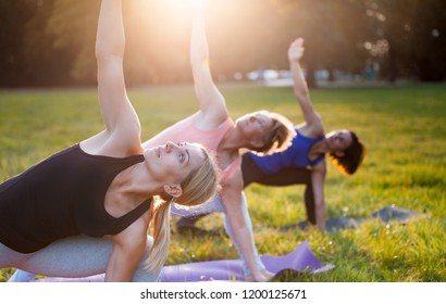 Yoga At Park, Group Of Mixed Age Women Doing Pose While Sunset