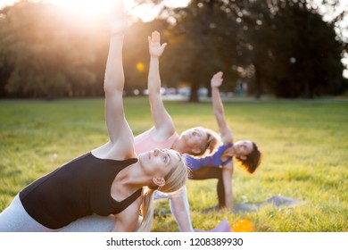 Yoga At Park, Group Of Mixed Age Women Doing Pose While Sunset
