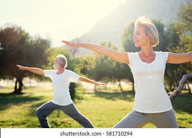 Yoga at park. Senior family couple exercising outdoors. Concept of healthy lifestyle. - Shutterstock ID 581710294