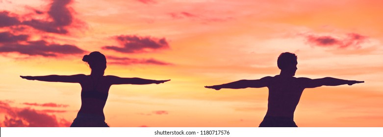Yoga people training meditating in warrior pose at sunset background panoramic banner. Silhouette of healthy athletes.