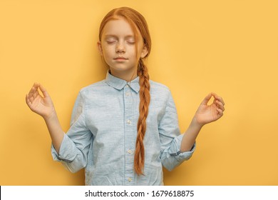 Yoga. Portrait Of Calm Relaxed Caucasian Red Haired Girl In Casual Wear, Isolated Over Yellow Background. Child With Freckles Keep Calm With Closed Eyes