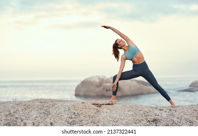 Yoga is a powerful vehicle for change. Shot of a sporty young woman practicing yoga at the beach. - Powered by Shutterstock