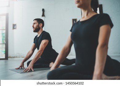 Yoga Practice Exercise Class Concept. Two beautiful people doing exercises.Young woman and man practicing yoga indoors