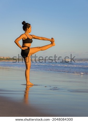 Yoga practice on the beach. Utthita Hasta Padangusthasana, Extended Hand-to-Big-Toe Pose. Standing balancing asana. Fit body. Healthy lifestyle. Support immune system. Copy space. Seminyak beach, Bali