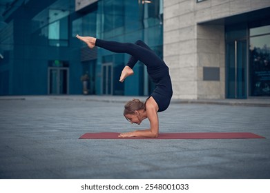 Yoga practitioner performs an advanced pose on a mat in an urban setting during the evening