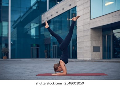 Yoga practitioner performs advanced pose outdoors in urban setting during early evening hours