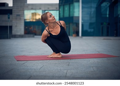 Yoga practitioner performs a challenging pose on a mat in an urban setting during the evening