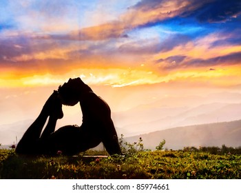 Yoga Raja Kapotasana backward bending pose by Man in silhouette on the grass outdoors at mountains and cloudy sky with sunrays background - Powered by Shutterstock