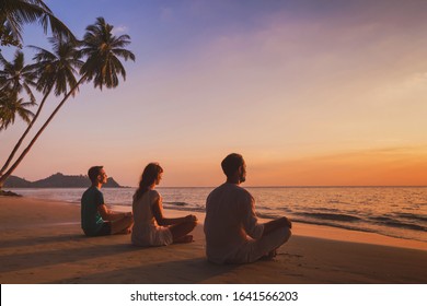 Yoga Retreat On The Beach At Sunset, Silhouettes Of Group Of People Meditating