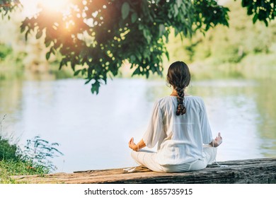 Yoga Retreat. Peaceful Young Woman Sitting In Lotus Position And Meditating By The Lake