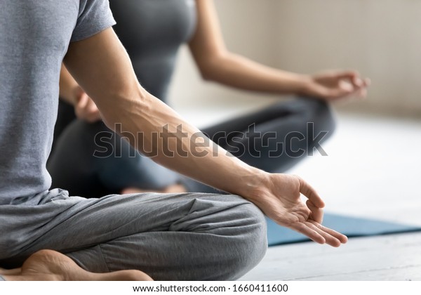 Yoga session process meditation practice close up\
focus on male fingers folded in mudra symbol. Concept of clarity of\
mind, improve inner balance, healthy lifestyle, serenity, internal\
calmness state