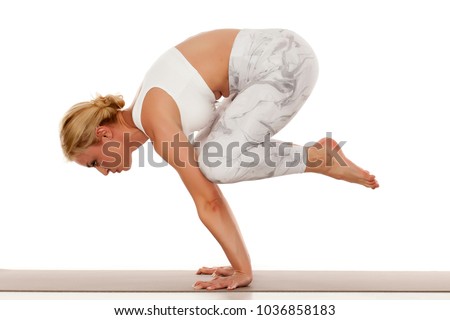 Yoga, sport, training and lifestyle concept - Young blonde woman in white sportswear doing yoga practice.Crane pose ,bakasana