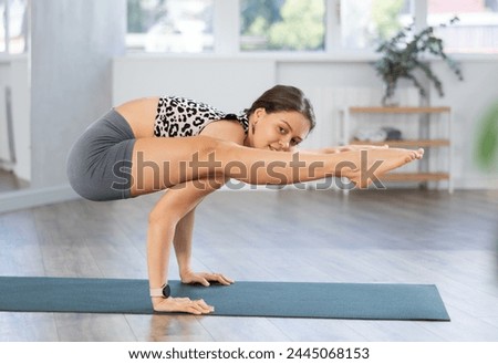 Yoga in sports studio hall. Girl performs bacasana asana