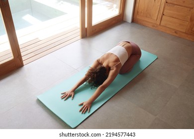 Yoga Stretch. Girl Practices Yoga Pose, Stretching Body At Home. Beautiful Woman With Fit Body Practicing Seated Forward Bend Position On Yoga Mat Indoors 