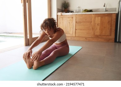 Yoga Stretch. Girl Practices Yoga Pose, Stretching Body At Home. Beautiful Woman With Fit Body Practicing Seated Forward Bend Position On Yoga Mat Indoors 