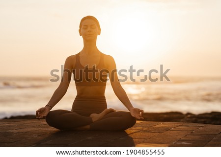 Yoga at sunset on the beach. woman performing asanas and enjoying life on the ocean. Bali Indonesia.