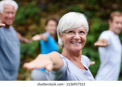 Yoga takes me to my happy place. Shot of a senior woman doing yoga with other people outdoors.