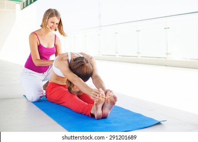 yoga teacher helping woman do the asana