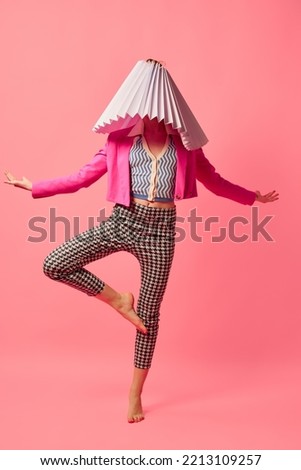 Yoga. Weird people concept. Creative portrait of young girl in avant-garde style image isolated over pink background. Vivid style, queer, art, fashion Stylish model in white lampshade.