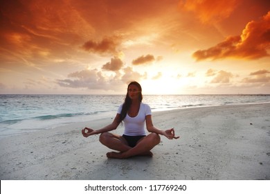 Yoga Woman In Lotus Pose On Beach At Sunset