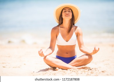 Yoga Woman Meditating At Serene Beach Sunset. Girl Relaxing In Lotus Pose In Calm Zen Moment In The Ocean Water During Yoga Holidays Resort Retreat. Multiracial Girl.