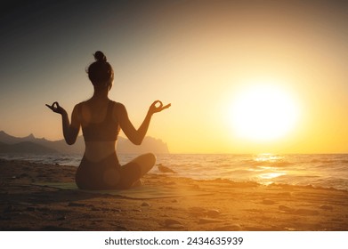 Yoga woman meditating at serene sunset or sunrise on the beach. The girl relaxes in the lotus position. Fingers folded in mudras. - Powered by Shutterstock