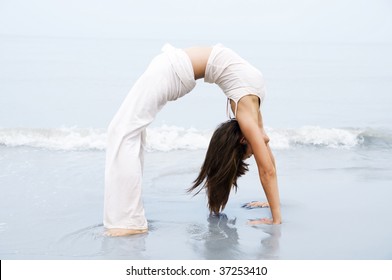 Yoga. Woman practicing Bridge Position Yoga on the beach.