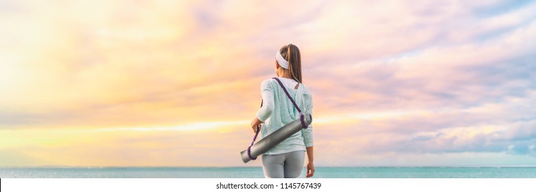 Yoga woman walking with exercise mat on morning sunrise sky background in serenity and tranquility panoramic banner. Active sport and fitness lifestyle.
